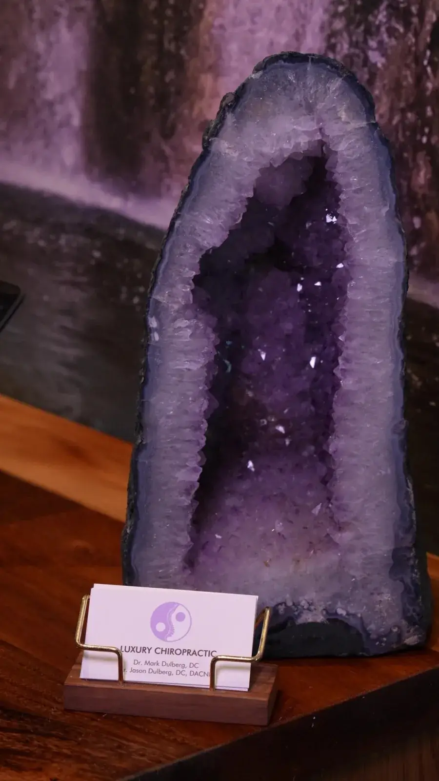 An amethyst cathedral beside the practice's cards at the Luxury Chiropractic front desk.