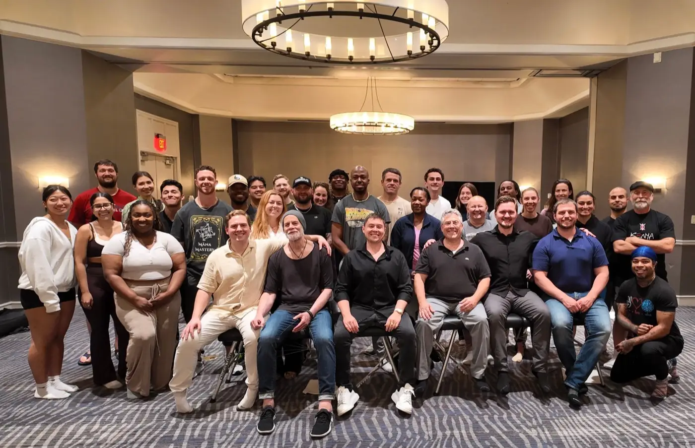 Podcast About thirty five practitioners gathered under two chandeliers in a hotel ballroom, the front row seated.